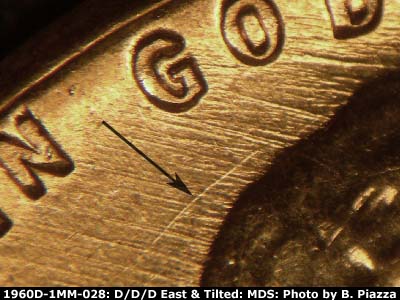 Die-stage B marker on 1960D•1MM•028 showing E/W die scratches under GOD, Curved SW die scratch behind hair.