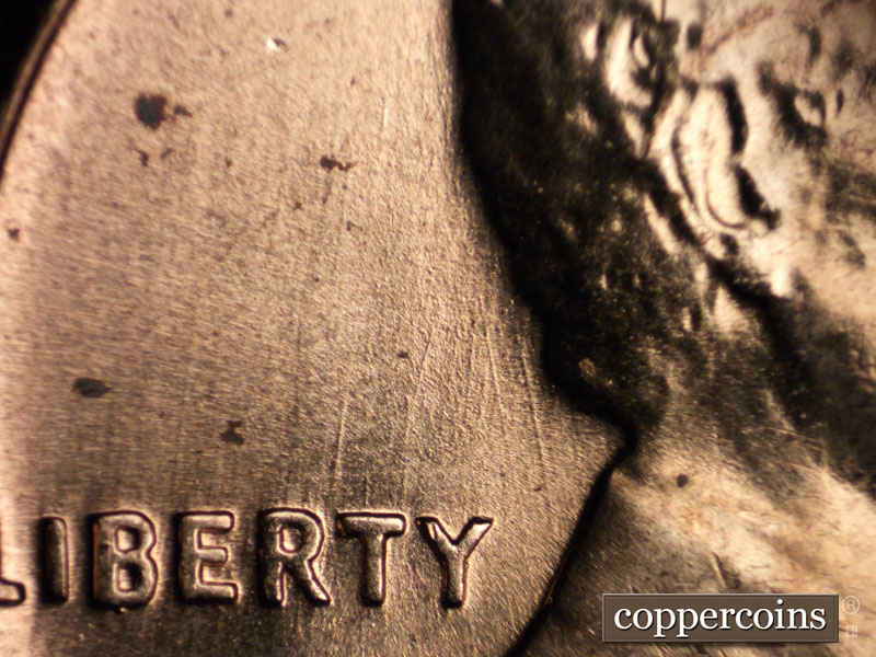 Die-stage B marker on 1960D•1MM•030 showing Pair of NNW die scratches between back of neck and Y in LIBERTY.