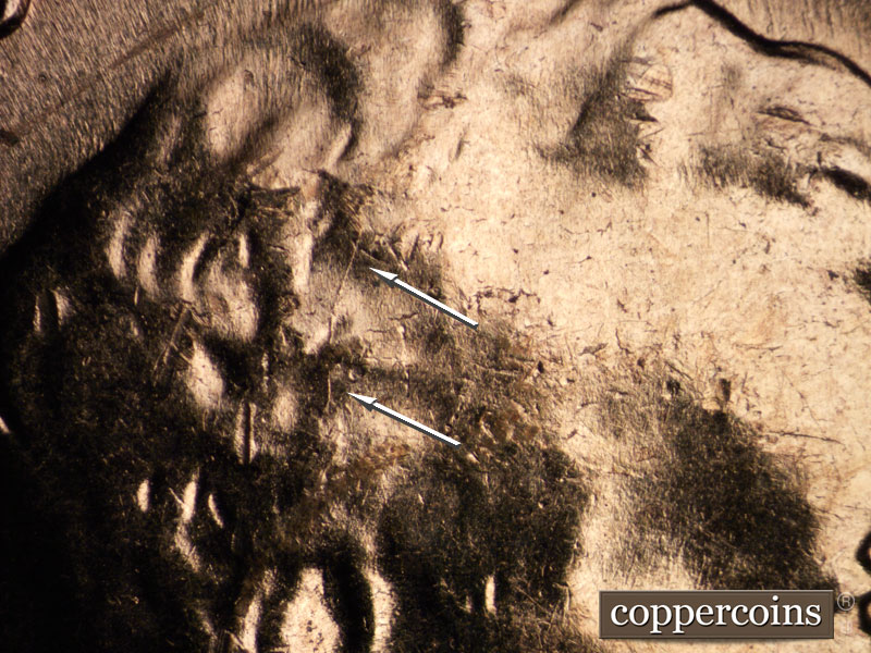 Die-stage B marker on 1960D•1MM•030 showing N/S die crack in hair. SSE die scratches in front of face.