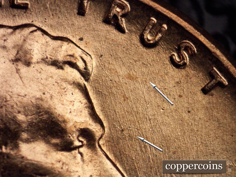 Die-stage A marker on 1960D•1MM•033 showing NE die scratch from tip of nose to U in TRUST. SSE die scratches in field in front of face.