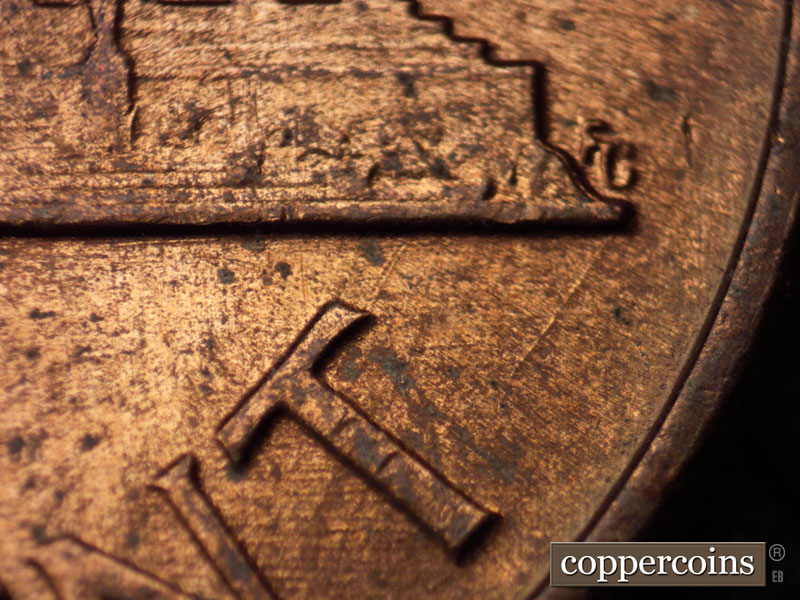 Die-stage B marker on 1960D•1MM•035 showing A die scratch runs SW from the lower right memorial base.