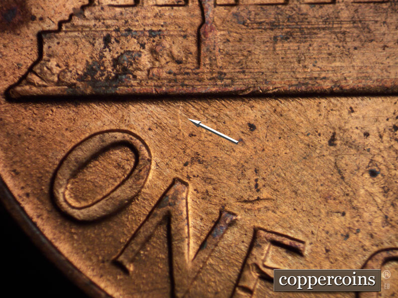Die-stage B marker on 1960D•1MM•036 showing Light die crack from base toward N in ONE.