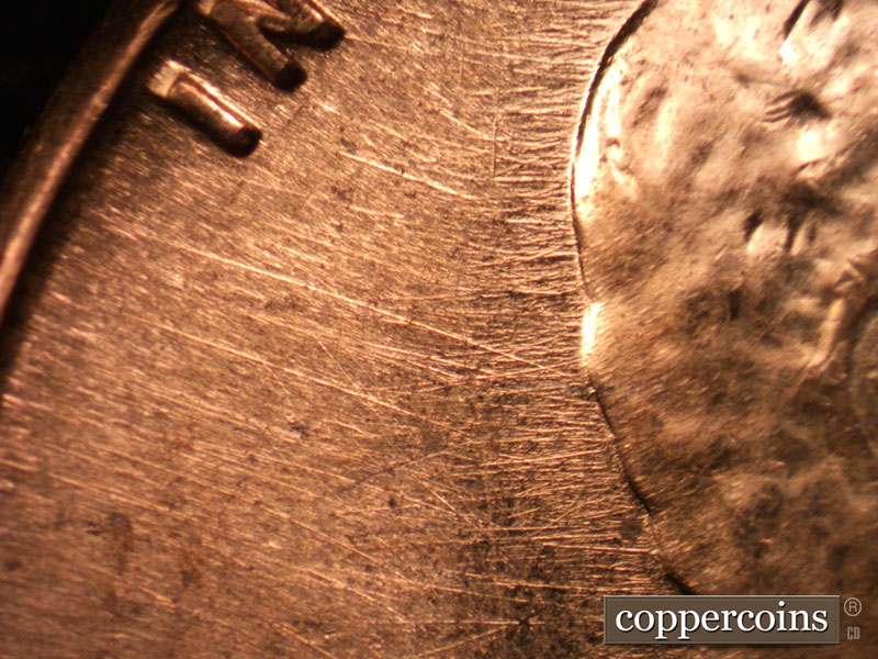 Die-stage C marker on 1960D•1MM•037 showing NW die scratches from back of head to rim.