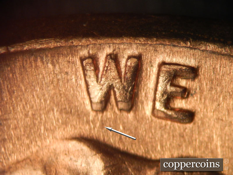Die-stage B marker on 1960D•1MM•038 showing NNE die scratch from top of hair to W in WE.