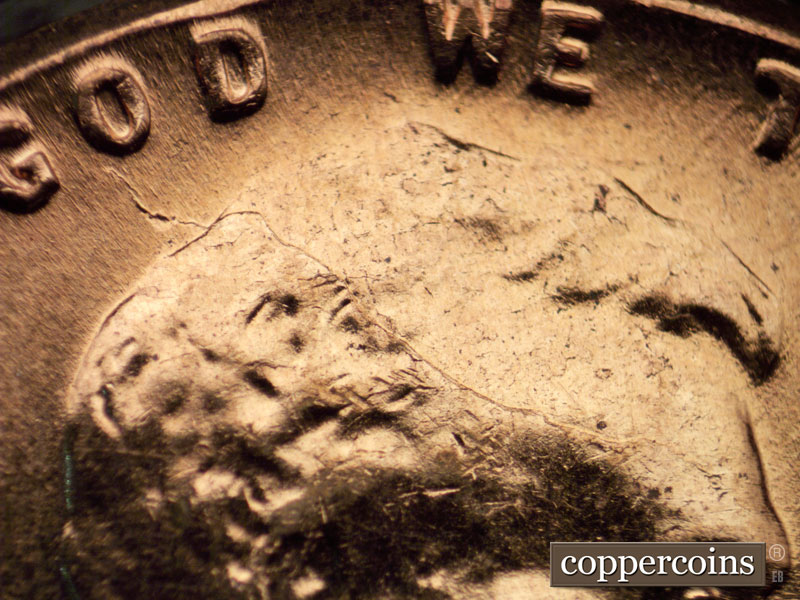 Die-stage C marker on 1960D•1MM•042 showing A very long die crack starts in the hair at the back of the head and curves down the back up across the forehead.