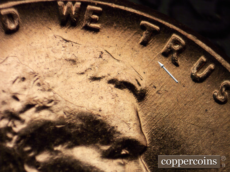 Die-stage C marker on 1960D•1MM•042 showing Many NE-SW die scratches show above the hair in and around TRUST.
