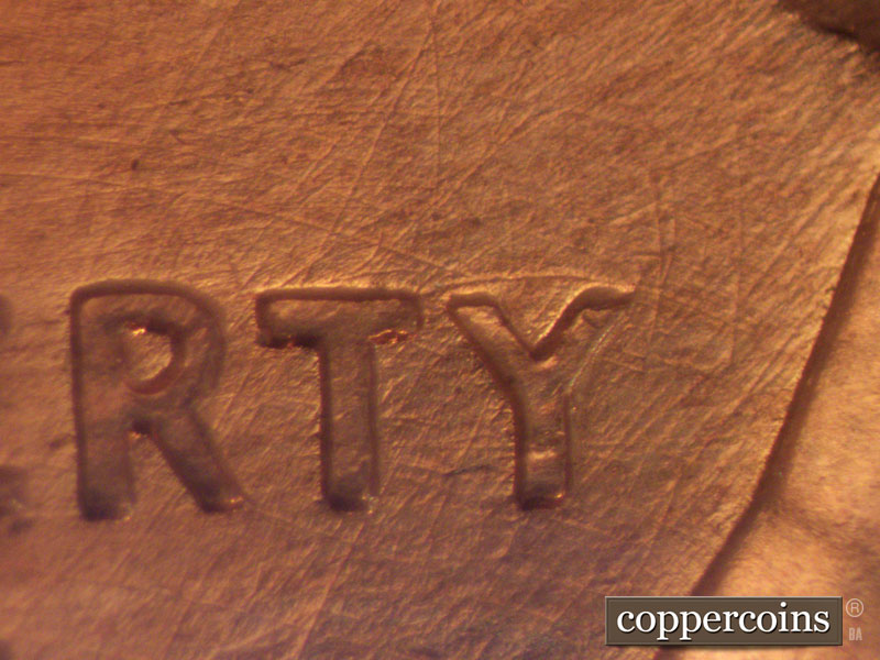 Die-stage B marker on 1960D•1MM•044 showing Numerous die scratches through LIBERTY with large arching die scratch over Y of LIBERTY.