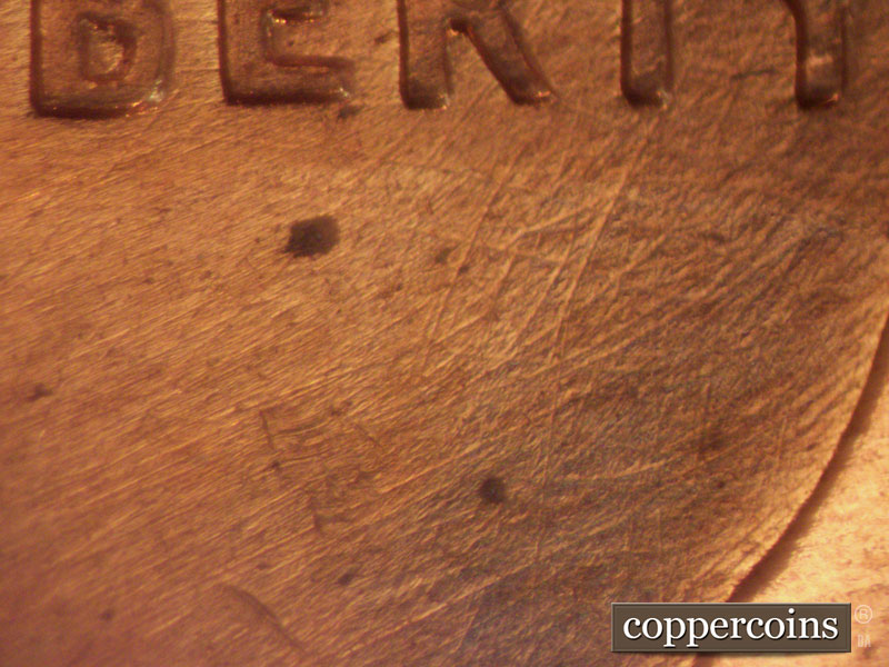 Die-stage B marker on 1960D•1MM•044 showing Heavy diagonal die scratches above and below LIBERTY,.