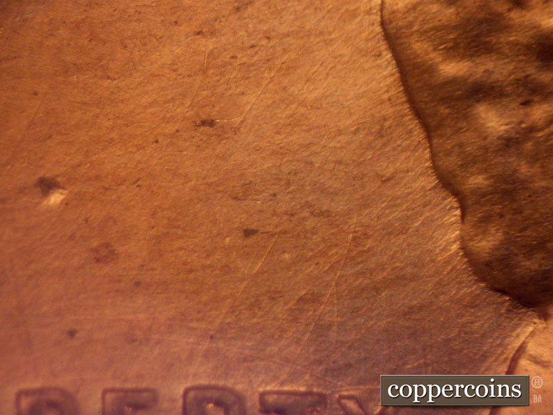 Die-stage B marker on 1960D•1MM•044 showing Die scratches in field behind head.