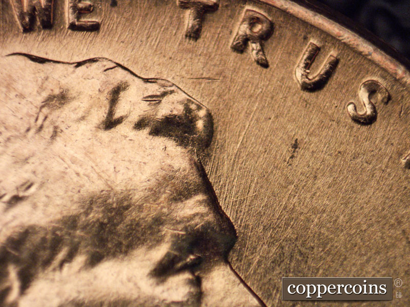 Die-stage A marker on 1960D•1MM•048 showing NNE die scratches from forehead toward rim.