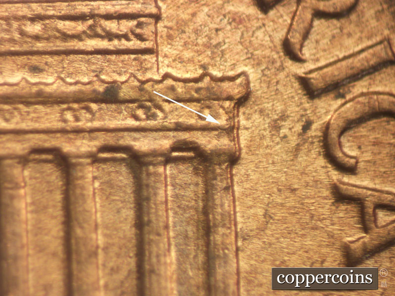 Die-stage B marker on 1960D•1MM•049 showing Die chipping starting on right cornice.