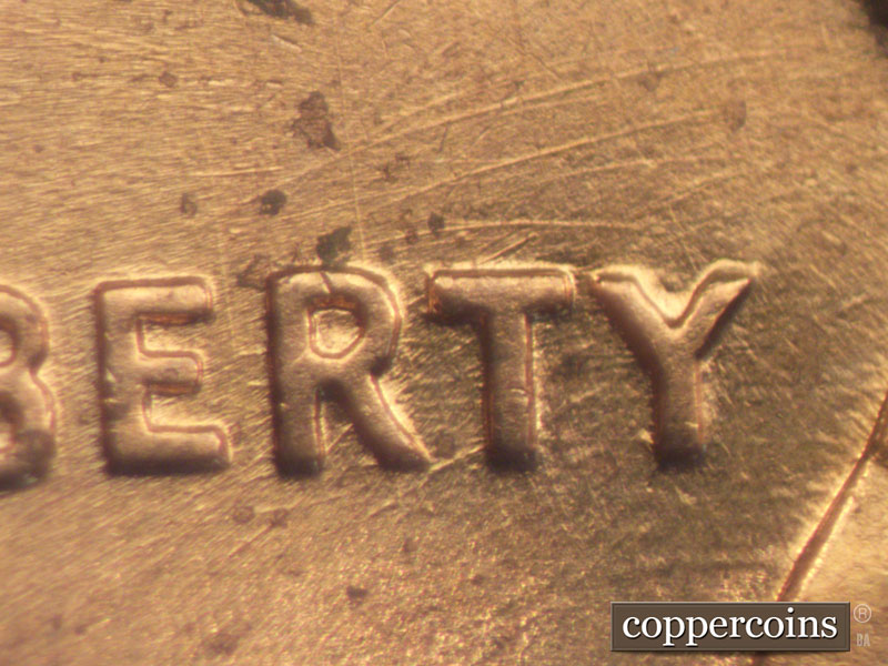 Die-stage B marker on 1960D•1MM•050 showing Group of curved die scratches through and above RTY in LIBERTY.