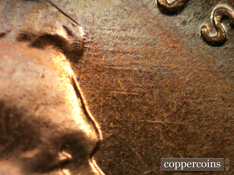 Die-stage C marker on 1960D•1MM•050 showing Worn E/W die scratches in front of forehead.