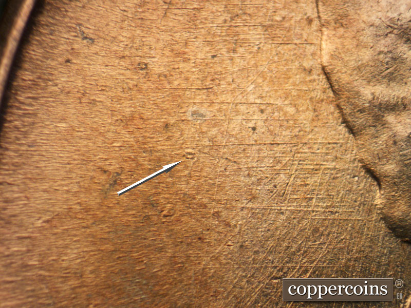 Die-stage B marker on 1960D•1MM•053 showing Die gouge in field behind head. Die scratches in field behind head.