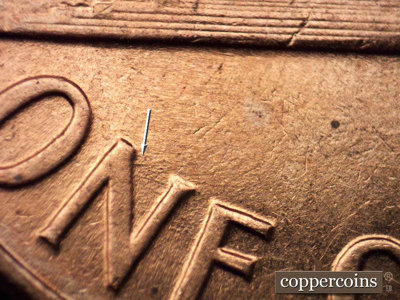 Die-stage B marker on 1960D•1MM•058 showing E/W die gouge from near top of N in ONE.