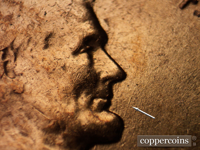 Die-stage B marker on 1960D•1MM•061 showing NNE die scratch from chin toward last T in TRUST.