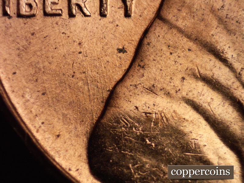Die-stage A marker on 1960D•1MM•064 showing NNE die scratches from shoulder toward and through LIBERTY.