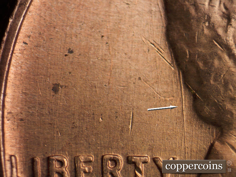 Die-stage C marker on 1960D•1MM•072 showing Heavy slightly curve die gouge behind hair.