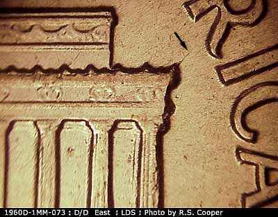 Die-stage C marker on 1960D•1MM•073 showing A small die crack runs NE from the right cornice.
