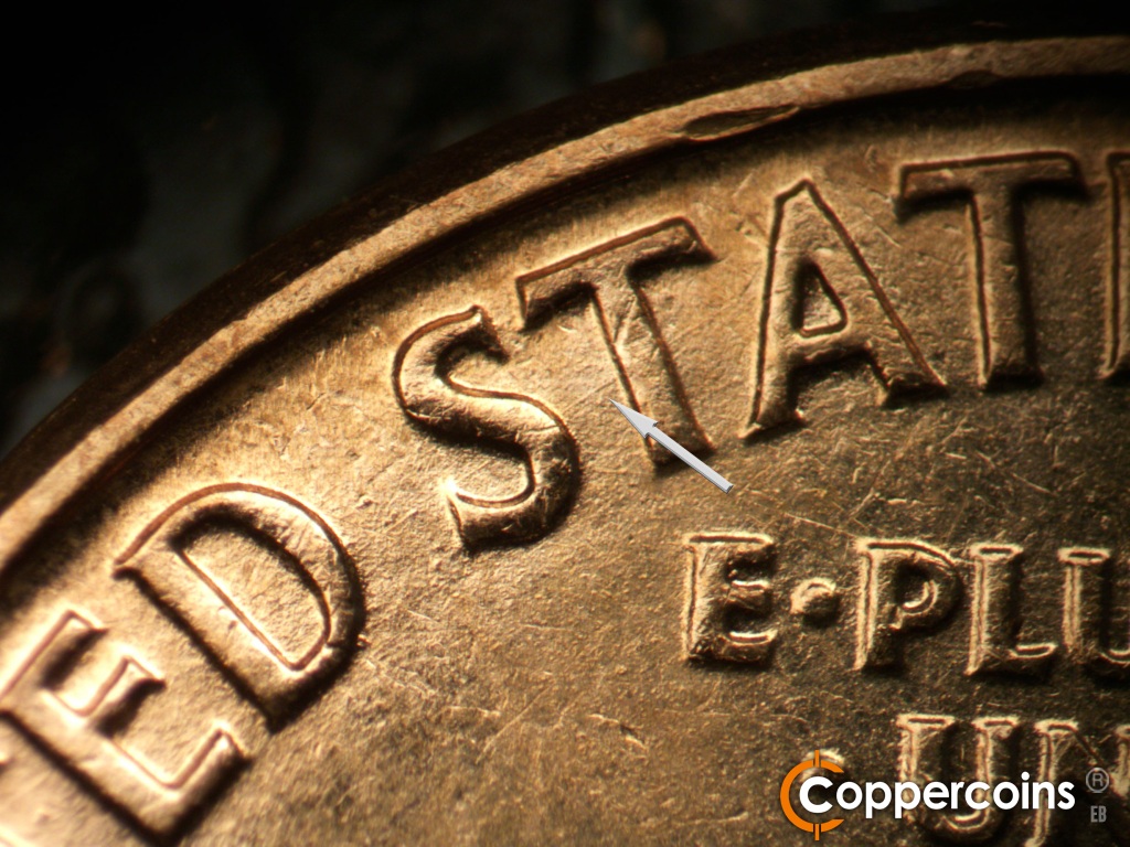 Die-stage B marker on 1960D•1MM•173 showing A long die scratch starts just above the die dot and runs to the top of the second T of STATES.