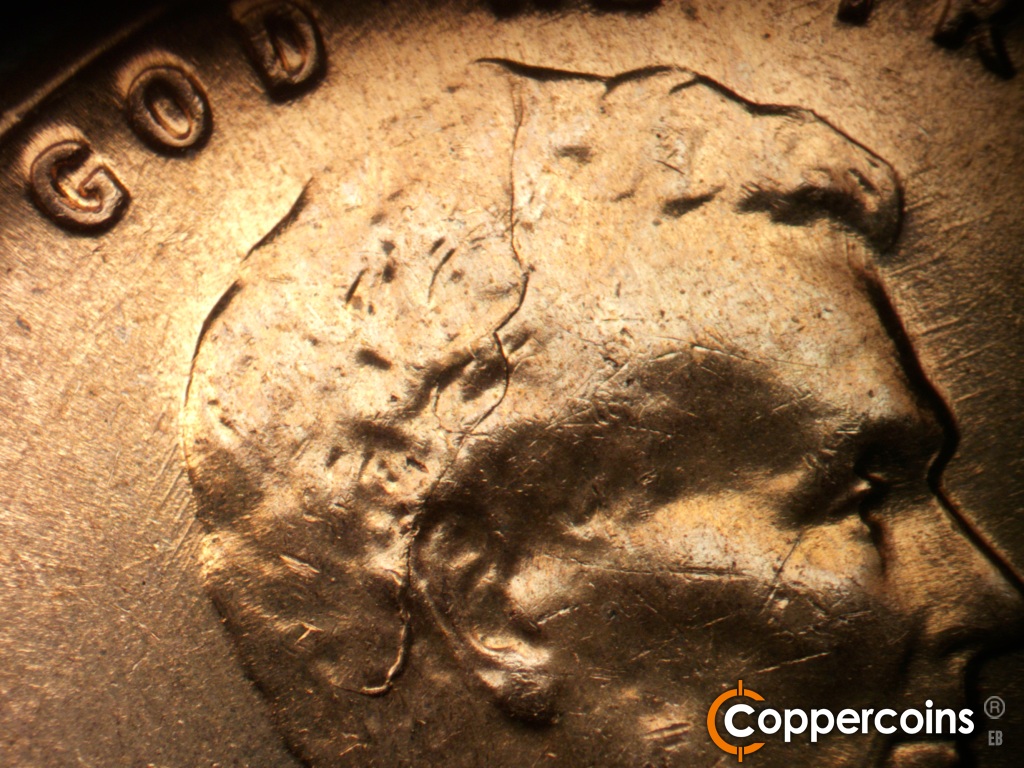 Die-stage C marker on 1960D•1MM•296 showing Large die crack ftom behind ear up toward W in WE.