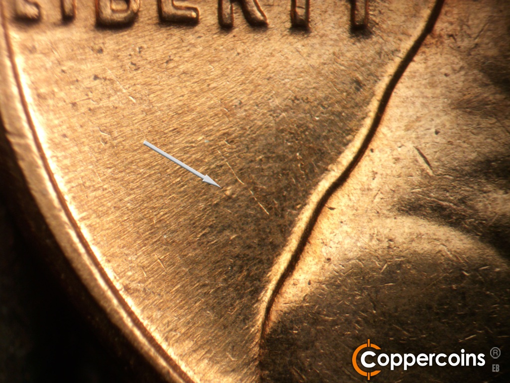 Die-stage C marker on 1961D•1MM•139 showing Die dot in field behind shoulder.