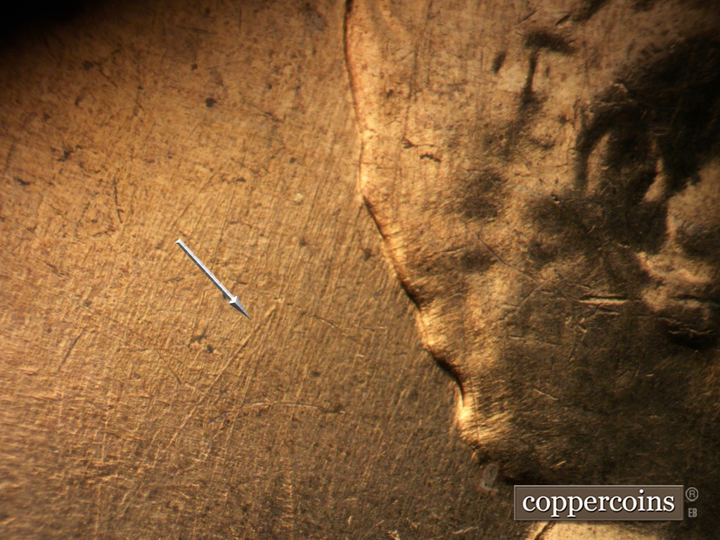 Die-stage A marker on 1962D•1MM•008 showing SW die scratch in field behind head.