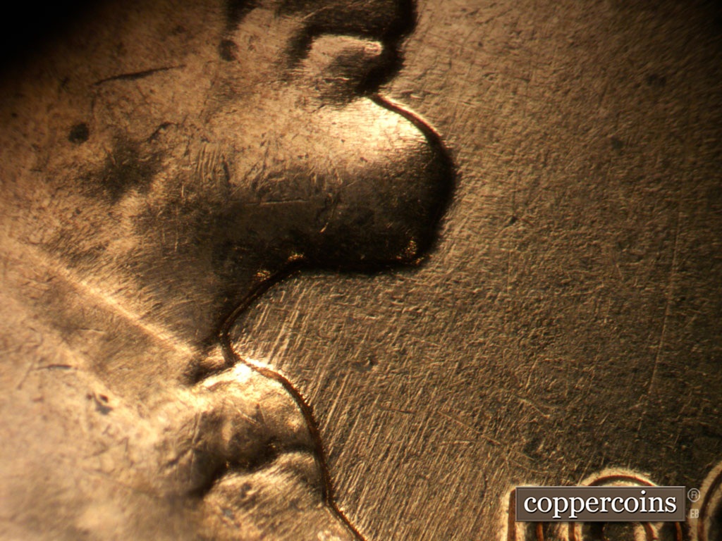 Die-stage A marker on 1962D•1MM•008 showing NE die scratches under chin.