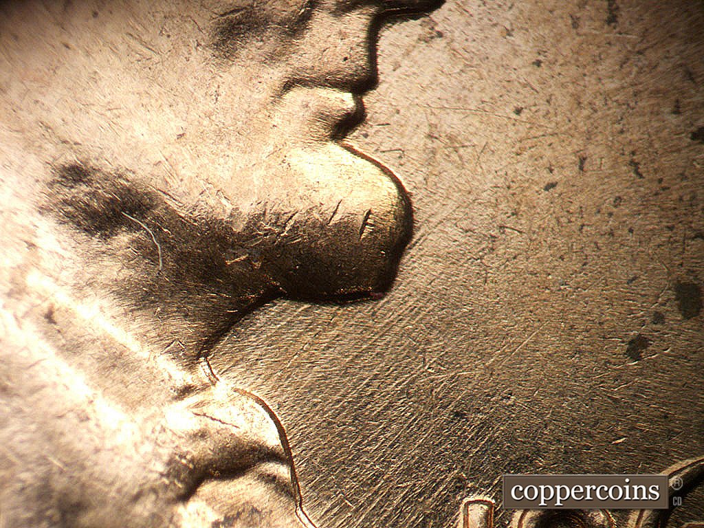 Die-stage B marker on 1962D•1MM•038 showing NE die scratches from throat.