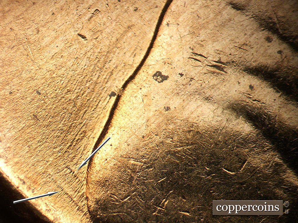 Die-stage B marker on 1964D•1MM•040 showing NE die gouges from bottom of shoulder, SW die scratches in field behind shoulder.