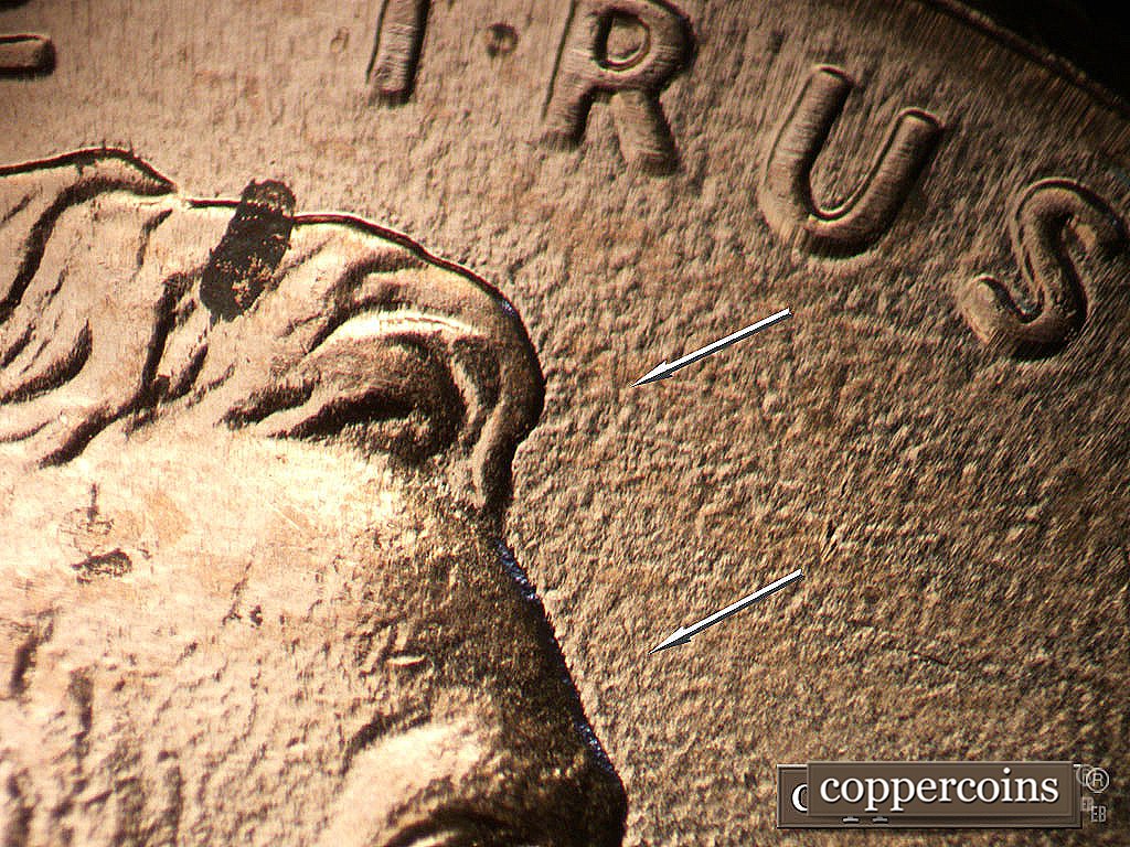 Die-stage B marker on 2003P•1DR•017 showing NNW die scratch in front of forehead.