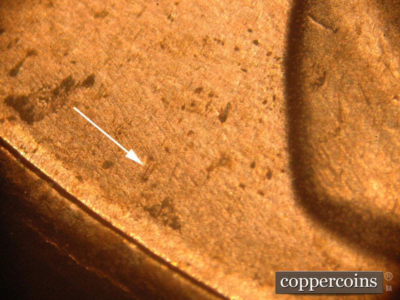 Die-stage B marker on 2016P•1DO•014 showing NE to SW die scratches near the rim.