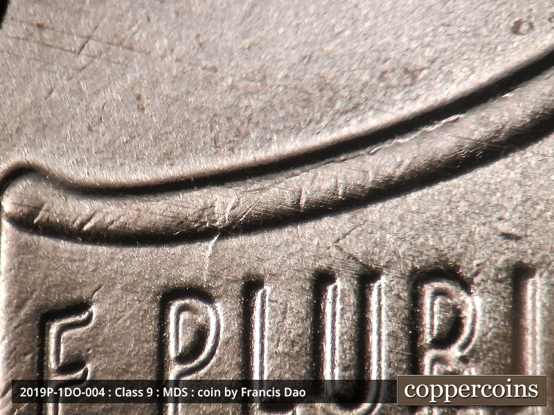 Die-stage B marker on 2019P•1DO•004 showing A die scratch runs along the top of the shield and continues south to the P.