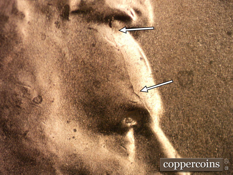 Die-stage B marker on 2020D•1DR•002 showing Die crack runs along the front of the forehead with a significant die chip at the hair line.