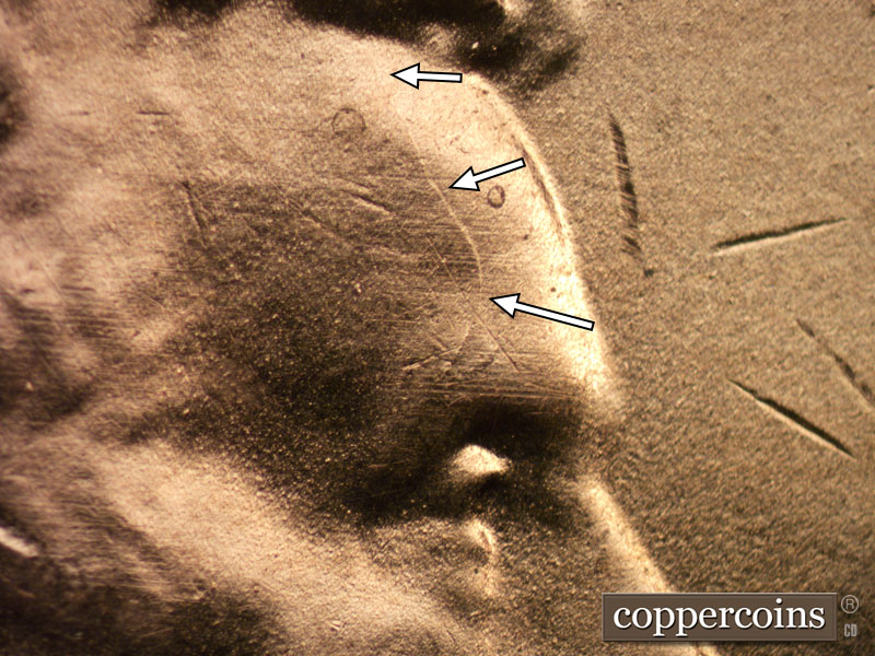 Die-stage B marker on 2020D•1DR•003 showing A curved die crack above the eye area.