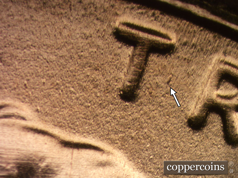 Die-stage B marker on 2020D•1DR•003 showing Heavy die gouge between the T and R of TRUST.