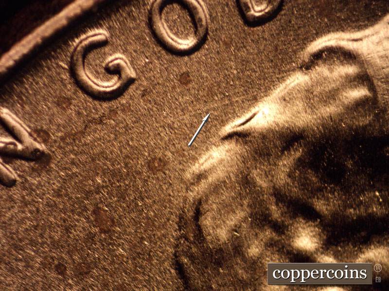 Die-stage B marker on 2020P•1DO•003 showing WSW die scratch from hair toward rim.
