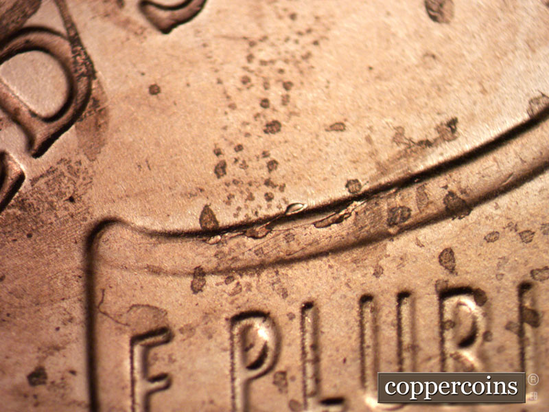 Die-stage C marker on 2021P•1DO•001 showing Die crack on left top of shield.