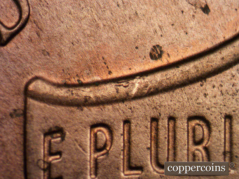 Die-stage C marker on 2021P•1DO•002 showing Die crack on upper left of shield.
