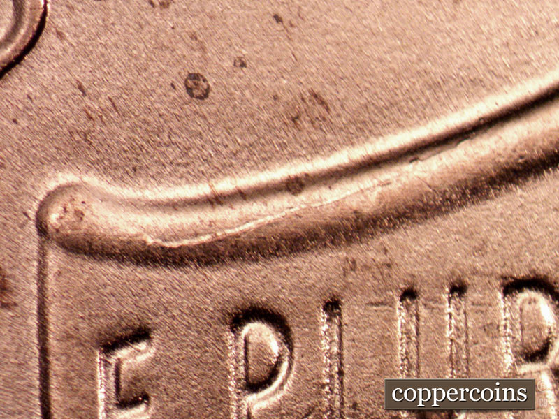 Die-stage B marker on 2022D•1DR•001 showing Die crack along left top of shield.