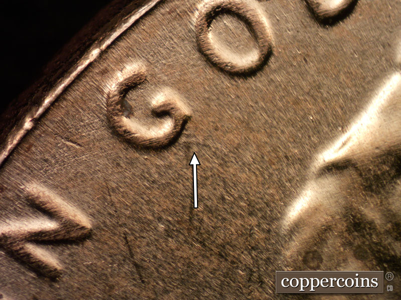 Die-stage B marker on 2023D•1DR•001 showing SSE die scratches extend from bottom of G in GOD.