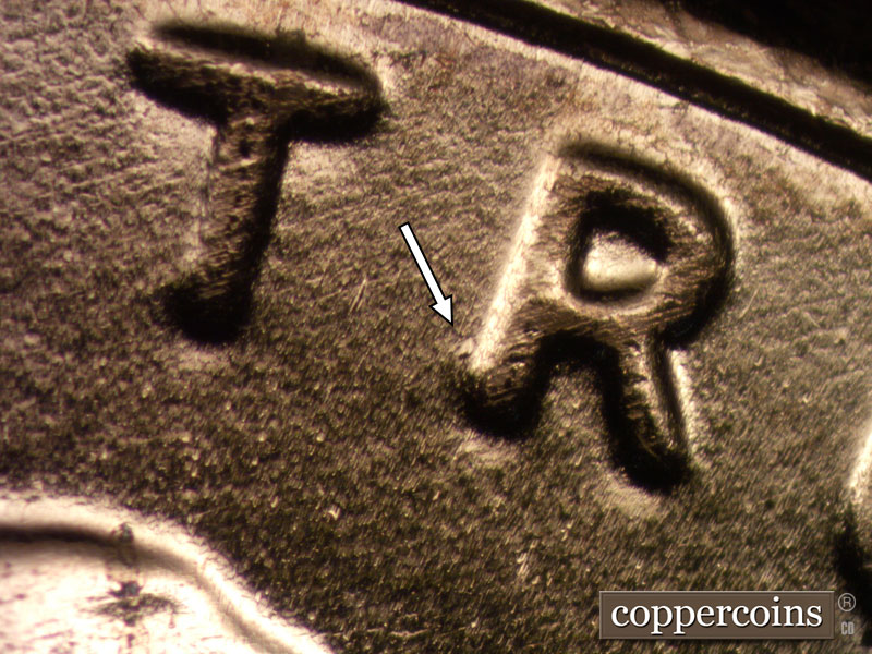 Die-stage B marker on 2024D•1DO•002 showing Die dot near R in TRUST.