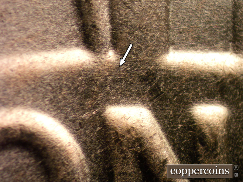 Die-stage B marker on 2024D•1DO•002 showing E/W die scratch above N in ONE.
