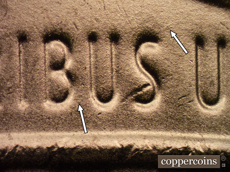 Die-stage B marker on 2024D•1DR•001 showing A die scratch extends east from the bottom of the B and diagonally NE from the top of the S of PLURIBUS.