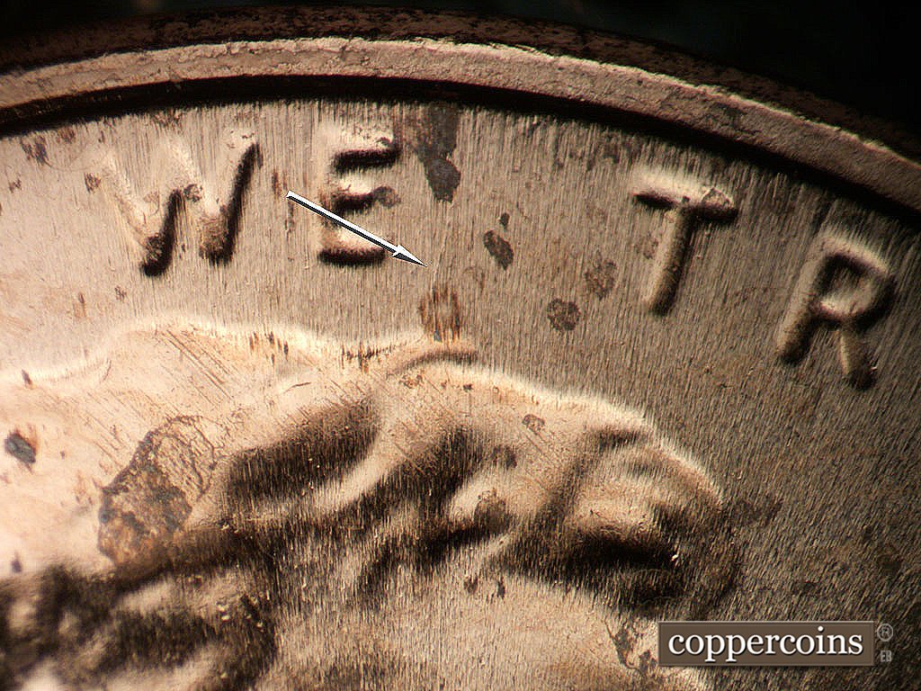 Die-stage B marker on 2024P•1DR•001 showing NNE die scratch from top of hair between WE and TRUST.