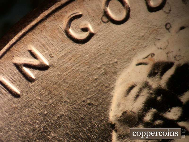 Die-stage B marker on 2025P•1DO•001 showing NE die scratches through IN GOD.